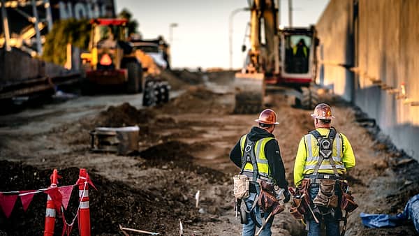 Two construction workers on a high building site looking out over the city