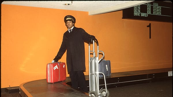 An unidentified airport employee, a Skycap porter, is seen by a baggage carousel