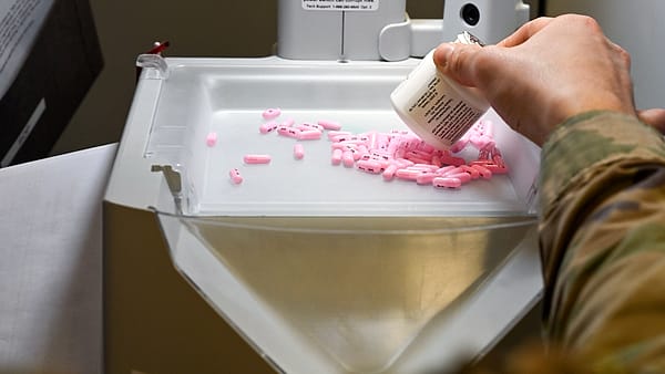 A 52nd Medical Group pharmacist uses an automated pill counter to fill prescription orders at Spangdahlem Air Base, Germany