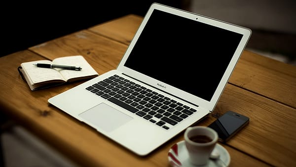 A home office workstation with a desk, a chair and a screen set against the wall of a domestic room