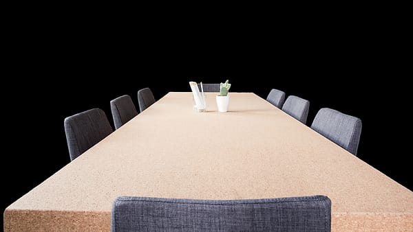 An empty meeting table with chairs drawn up around it, ready for a negotiation that has not begun