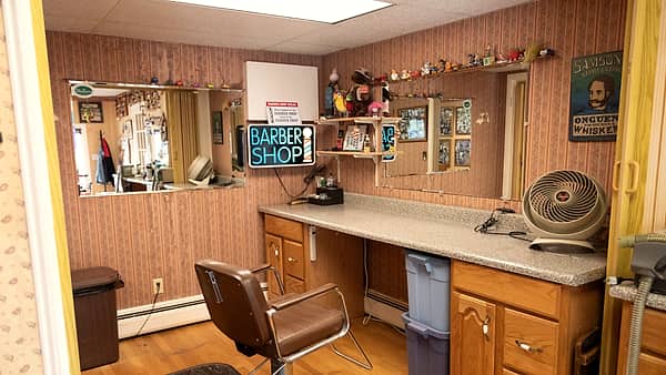 Interior at The Village Barber in Weston , Massachusetts , showing a single hydraulic barber chair, a long laminate counter