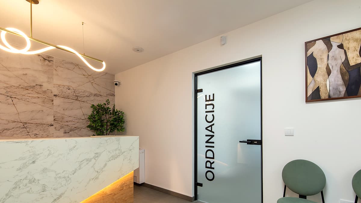 A modern reception area with a counter, seating along one wall and a corridor leading away from the waiting space